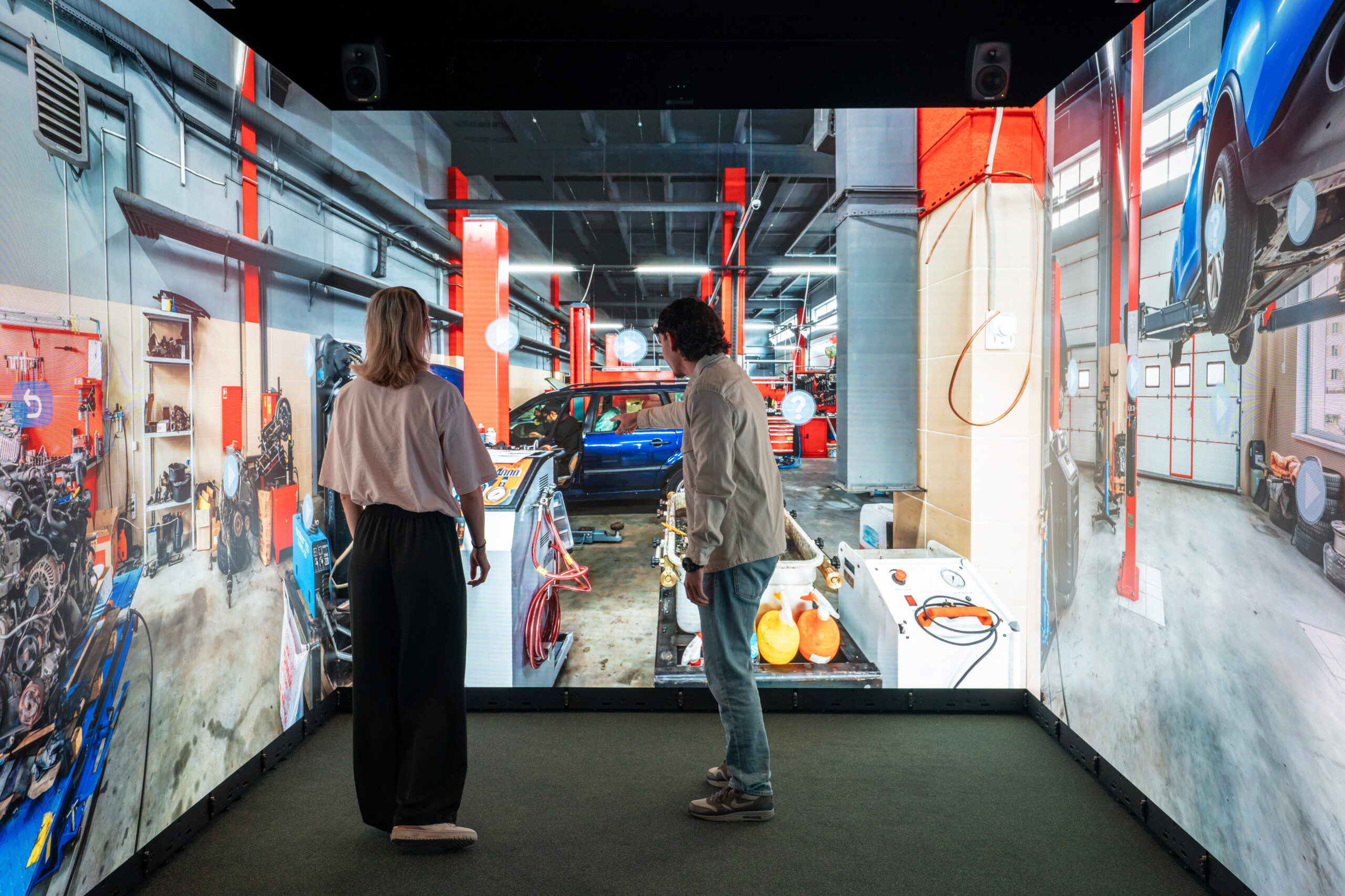 People exploring an interactive automotive workshop simulation inside an Immersive Room