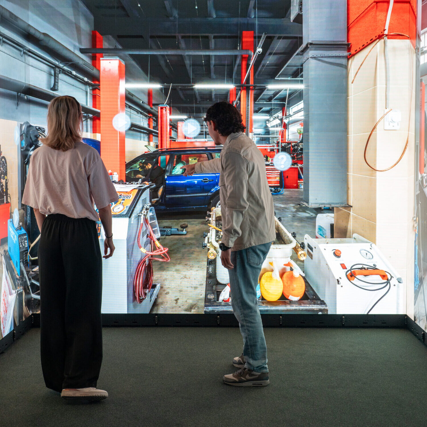 Visitors exploring an interactive automotive workshop in an Immersive Room